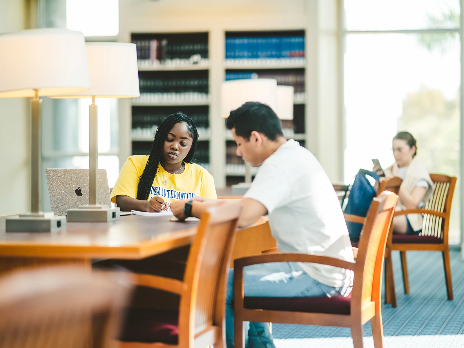 Two FIU students working at a desk in the library